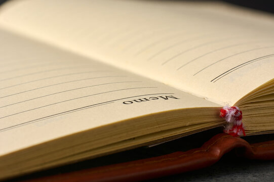 open lined memo book with leather cover on dark surface, blank yellowish paper pages in close-up view with copy space, business planning and journaling concept