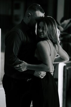 Romantic couple embracing closely during a quiet indoor evening in a dark and moody setting