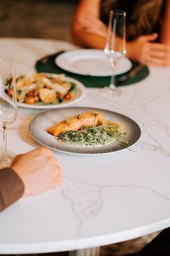 Couple enjoying a gourmet salmon dinner with wine at a fine dining restaurant during the evening