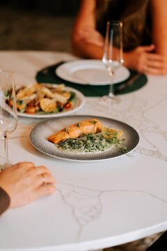 Salmon fillet with creamy spinach served on a white marble table during a romantic evening dinner