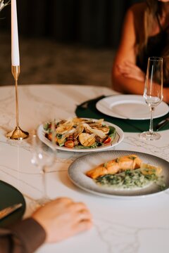 A romantic candlelit salmon and salad dinner on a marble table