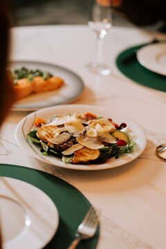 Fresh salad with shaved cheese served on a round plate during a formal dinner party at a restaurant