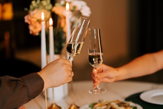 Couple toasting with glasses of champagne at a candlelit dinner during the evening indoors
