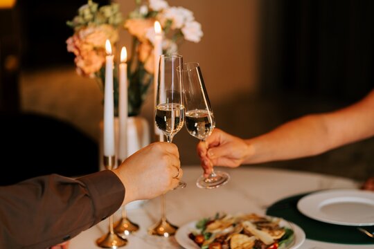 Couple toasting with champagne flutes during a romantic candlelit dinner at a restaurant at night