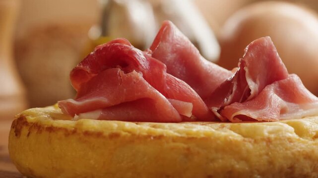 Spanish omelette with jamon serrano, tortilla and iberico cured ham appetizer on wooden table, traditional Spanish breakfast close up in cafe