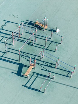Aerial view of the calisthenics park at Krimulda Secondary School Stadium featuring metal exercise bars and fitness equipment on a green surface in Ragana, Sigulda Municipality, Latvia.