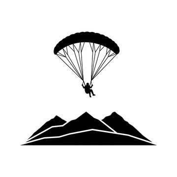 Paraglider silhouette flying with a parachute over mountain peaks