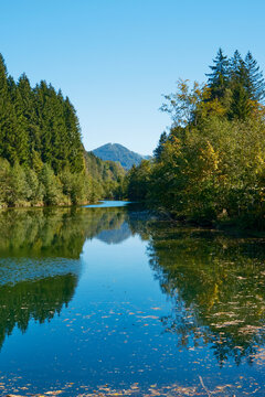 Scenic view across the Weissach reservoir surrounded by green hills and forest in the Allg&auml;u region near Oberstaufen, Bavaria, Germany.
