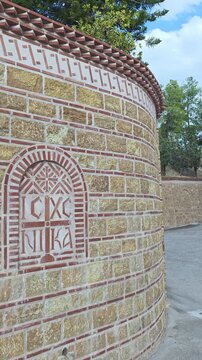 Byzantine-style cross with the inscription IC XC NIKA on a curved stone and brick wall of an Orthodox church on Aegina island, Greece. Vertical video.