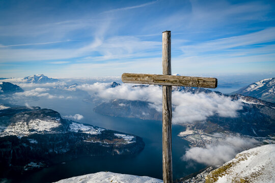 Weathered wooden summit cross above a cloudy lake