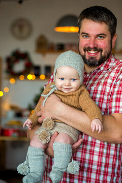 Happy family with a baby celebrating Christmas at home, enjoying cozy holiday moments together near a decorated Christmas tree in a warm festive atmosphere
