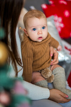 Happy family with a baby celebrating Christmas at home, enjoying cozy holiday moments together near a decorated Christmas tree in a warm festive atmosphere