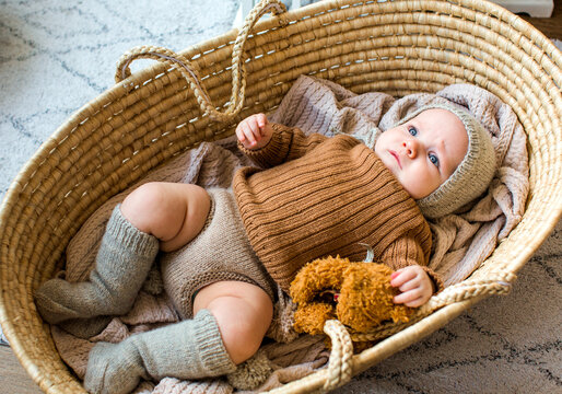 Cute baby dressed as Santa Claus at home during Christmas, enjoying a cozy festive atmosphere near a decorated Christmas tree.