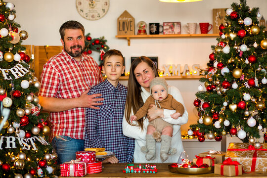 Happy family with a baby celebrating Christmas at home, enjoying cozy holiday moments together near a decorated Christmas tree in a warm festive atmosphere