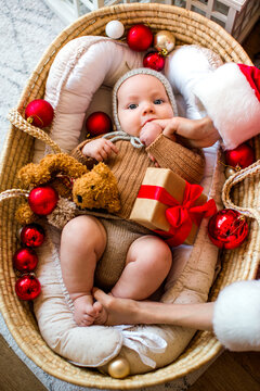 Cute baby and his teenage brother dressed as Santa Claus celebrating Christmas together at home in a cozy festive atmosphere.