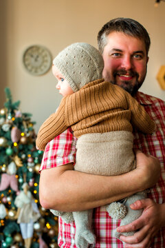 Happy family with a baby celebrating Christmas at home, enjoying cozy holiday moments together near a decorated Christmas tree in a warm festive atmosphere