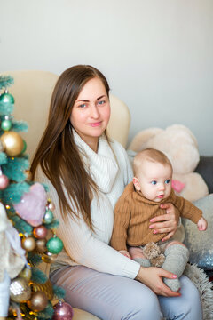 Happy family with a baby celebrating Christmas at home, enjoying cozy holiday moments together near a decorated Christmas tree in a warm festive atmosphere