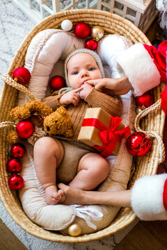 Cute baby and his teenage brother dressed as Santa Claus celebrating Christmas together at home in a cozy festive atmosphere.