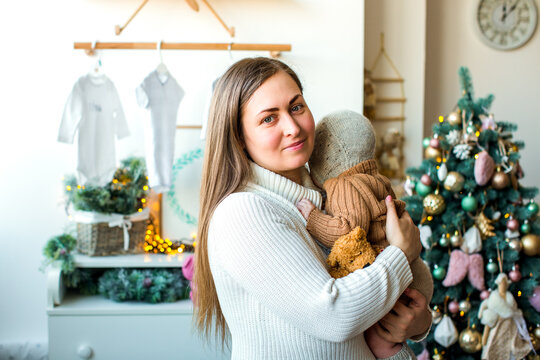 Happy family with a baby celebrating Christmas at home, enjoying cozy holiday moments together near a decorated Christmas tree in a warm festive atmosphere