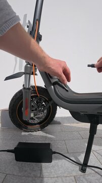 Hand Unplugging Charger Cable from Electric Scooter Port