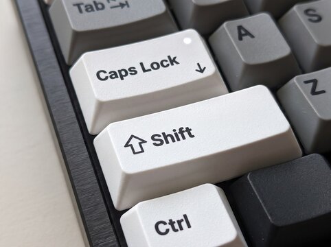 Close up view of white mechanical keyboard keys with caps lock and shift buttons.