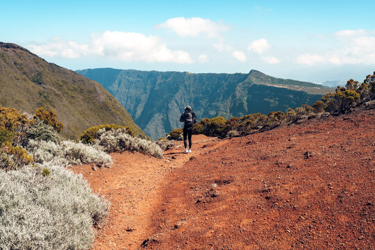 Woman Standing Above a Colorful Volcanic Canyon with Rust-Red Slopes and Rugged Mountain Cirques on Reunion Island