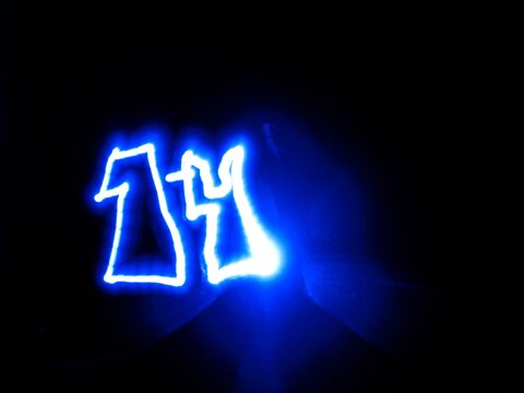 A blue neon light number fourteen drawn in light painting technique stands out against a pitch black backdrop. This abstract glowing electric digit is ideal for countdown and creative banner.
