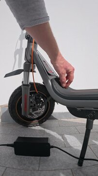 Person Plugging Power Cable into Electric Scooter Port