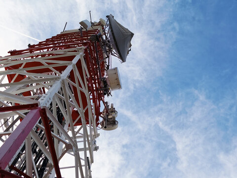 Low angle view of telecommunication tower with antennas against blue sky