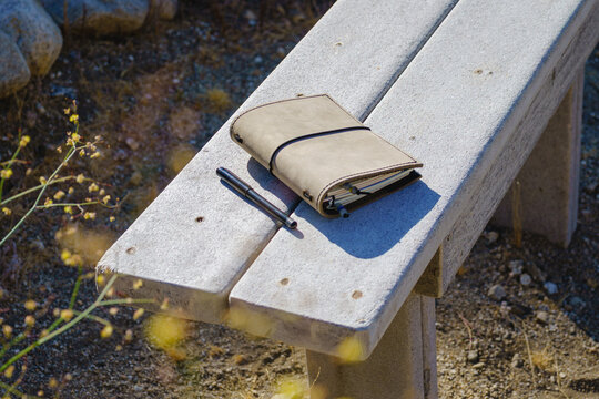 Suede leather nature journal and pen outdoors on a bench. Copy space.