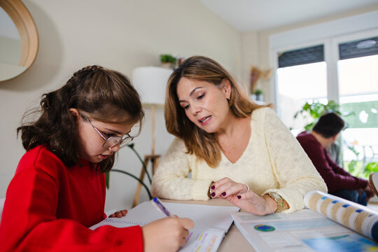 Mother helping daughter with homework at home learning