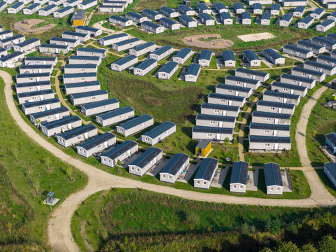 Aerial view of modern mobile homes arranged in rows within a holiday park featuring gravel paths and green lawns in The Netherlands.