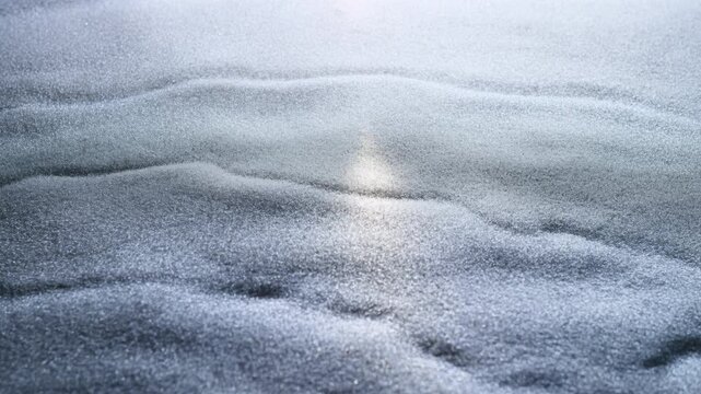 Rippling frozen surface glitters with fine snow beneath soft winter light