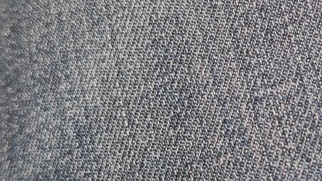 Detailed macro view of blue denim jeans textile. The camera slowly pans across the textured fabric, highlighting the classic diagonal weave