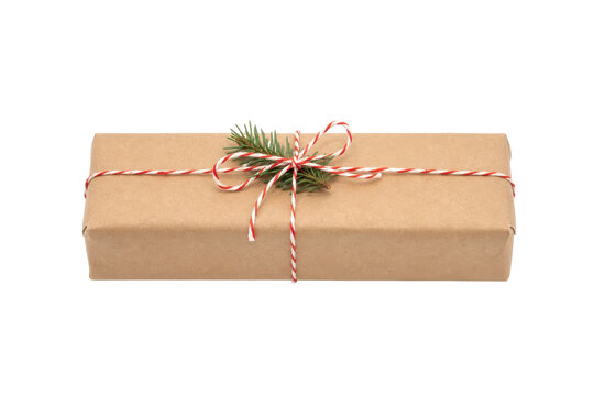 Rectangular brown paper gift box with red and white string and a small pine branch, isolated on a white background