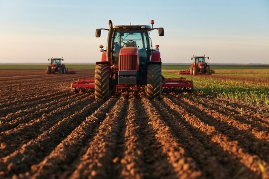 Synchronized tractors cultivating large farmland in parallel rows