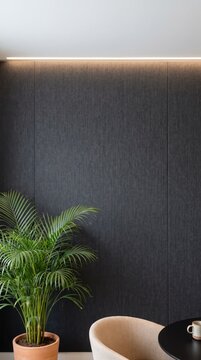 Refined charcoal fabric wall with LED cove light, areca palm, beige armchair and copy space