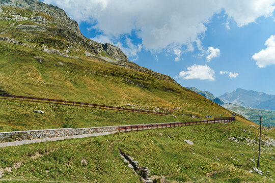 Winding road cuts through green mountain slopes in Italian Alps