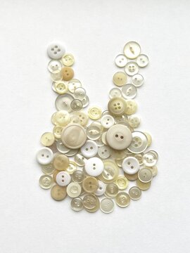 rabbit-shaped object made from button collage, rabbit face made with buttons, decorative illustration made with white buttons