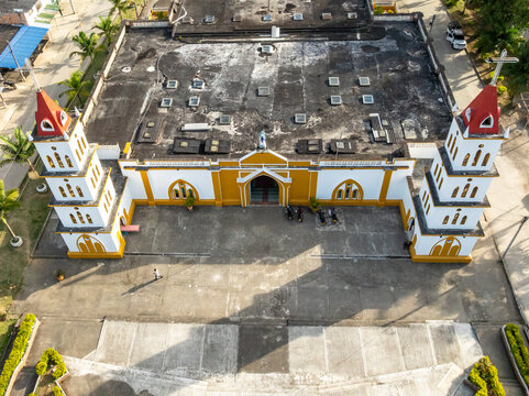 Aerial view of San Agustin church with its distinctive twin towers, yellow and white facade, and large courtyard in San Agustin, Huila, Colombia.