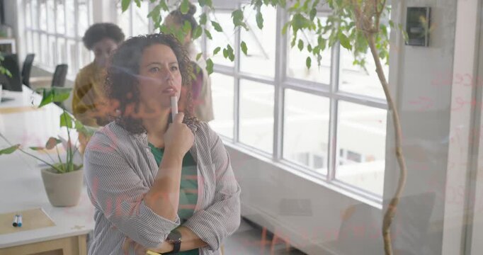African American woman in striped top holding marker, watching team sitting, writing ideas on glass