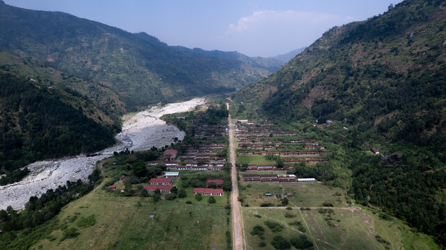 Aerial view of Kilembe nestled in a valley with a riverbed, surrounded by lush green mountains in Kilembe, Western Region, Uganda.