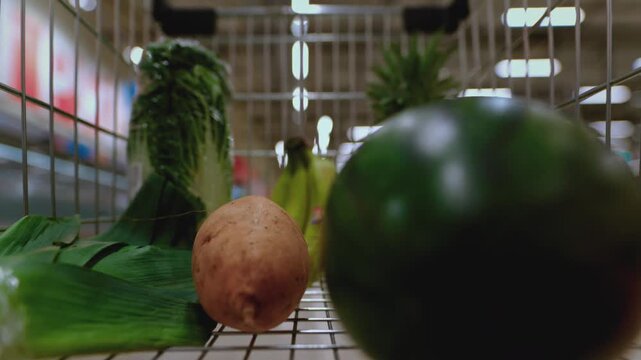 Timelapse of shopping cart moving through a supermarket as a customer selects fresh vegetables. Various products are added to Grocery trolley at supermarket. Healthy food, variety of vegetables