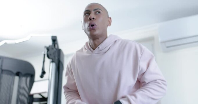 African American man adjusting grip, inhaling and lifting 8 kg kettlebell in home gym training