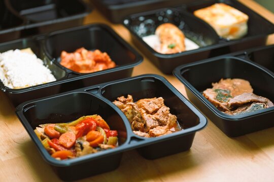 Food containers with various meal options arranged on a wooden table, illustrating choices in food distribution for acute food insecurity and risk of famine worldwide