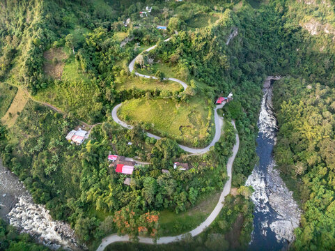 Aerial view of the Estrecho del Rio Magdalena with a winding road snaking through lush green hills and dense vegetation in San Agustin, Huila, Colombia.