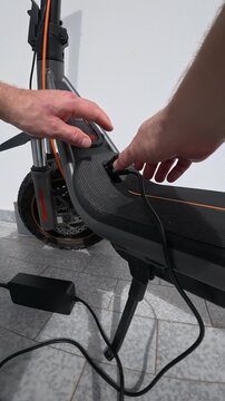 Hands Disconnecting Charging Cable from Electric Scooter Port