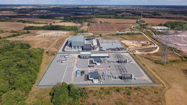 Aerial view of a massive 400 kV electrical substation with transformers, switchgear, and transmission pylons in Bramford, Suffolk, England, UK