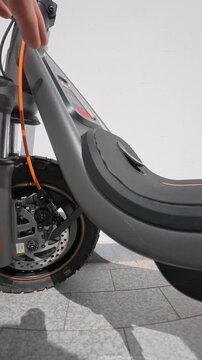 Hands Pulling out Charger Plug from Electric Scooter Port