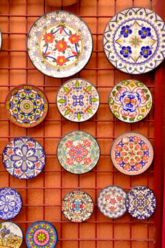 Colorful hand painted ceramic plates on terracotta tile wall